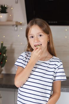 The girl eats cookies in the kitchen. Real life.