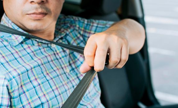 Safety belt for accident prevention. Driver hands fastening the seat belt, Close up of person hands putting on the seat belt. Driver's hands putting on the seat belt