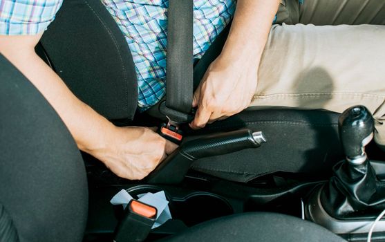 Close up of driver hands fastening the seat belt, Driver's hands putting on the seat belt. Safety belt for accident prevention. Close up of person's hands putting on the seat belt