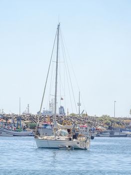 Yachts in the bay near the embankment with a lighthouse on a sunny day
