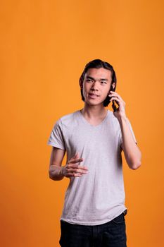 Young asian man chatting on smartphone, communication. Teenager talking on telephone, handsome person standing, having mobile conversation, answering phone call, medium shot