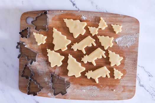 the process of cutting figures from shortcrust pastry for cookies with forms in the form of Christmas trees and animals