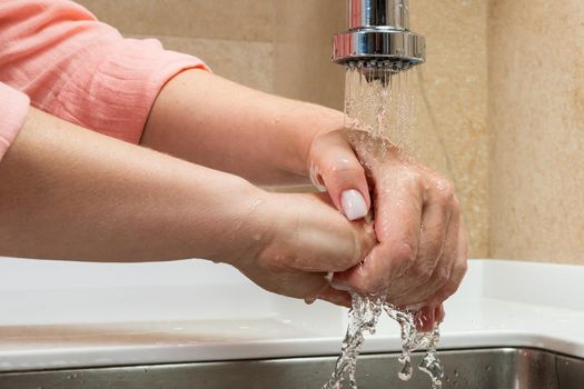 Close-up beautiful female hands under running water.