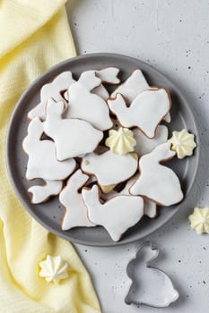 Easter cookies in the form of a rabbit on a gray plate with yellow textiles on a gray background. copy space,vertical photo