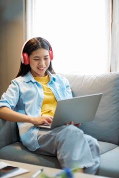 Close up of women working and studying using laptop at home. Women working, studying, researching using laptop while sitting on couch at home. Close up. Education and online learning concept.