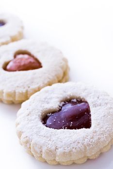 Linzer Torte cookies on white background with powdered sugar sprinkled on top.