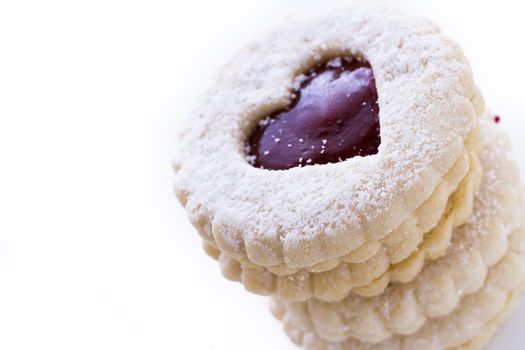 Linzer Torte cookies on white background with powdered sugar sprinkled on top.