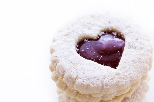 Linzer Torte cookies on white background with powdered sugar sprinkled on top.