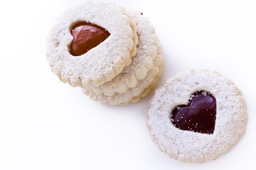 Linzer Torte cookies on white background with powdered sugar sprinkled on top.