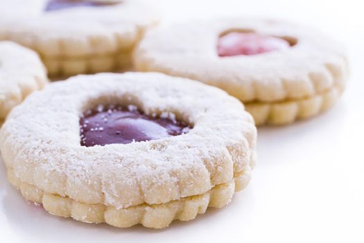 Linzer Torte cookies on white background with powdered sugar sprinkled on top.