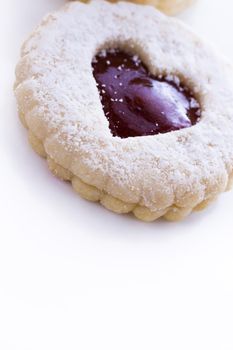 Linzer Torte cookies on white background with powdered sugar sprinkled on top.