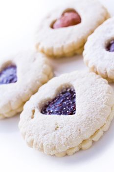 Linzer Torte cookies on white background with powdered sugar sprinkled on top.