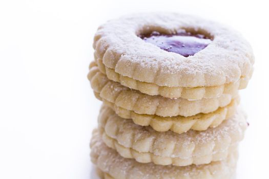 Linzer Torte cookies on white background with powdered sugar sprinkled on top.