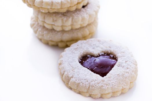 Linzer Torte cookies on white background with powdered sugar sprinkled on top.