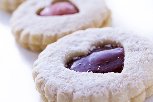 Linzer Torte cookies on white background with powdered sugar sprinkled on top.