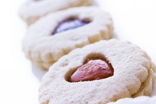 Linzer Torte cookies on white background with powdered sugar sprinkled on top.