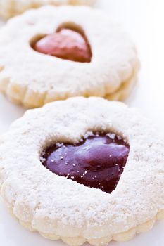 Linzer Torte cookies on white background with powdered sugar sprinkled on top.