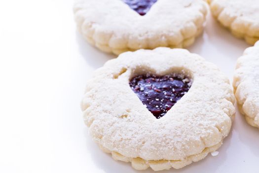 Linzer Torte cookies on white background with powdered sugar sprinkled on top.