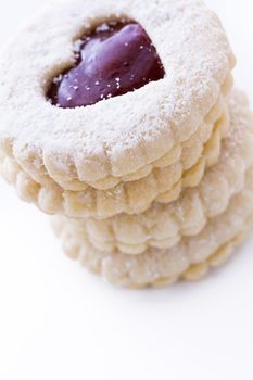 Linzer Torte cookies on white background with powdered sugar sprinkled on top.