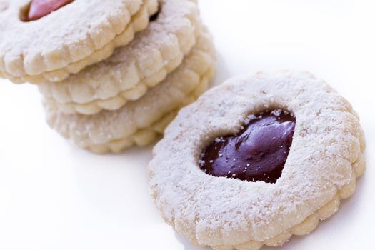 Linzer Torte cookies on white background with powdered sugar sprinkled on top.