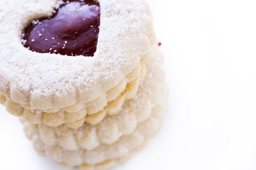 Linzer Torte cookies on white background with powdered sugar sprinkled on top.