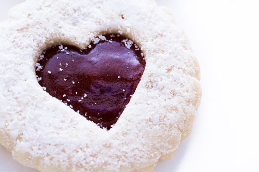 Linzer Torte cookies on white background with powdered sugar sprinkled on top.