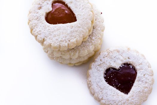 Linzer Torte cookies on white background with powdered sugar sprinkled on top.