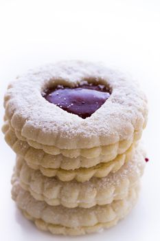 Linzer Torte cookies on white background with powdered sugar sprinkled on top.