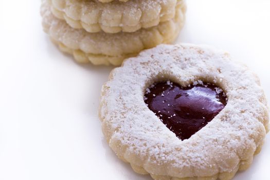 Linzer Torte cookies on white background with powdered sugar sprinkled on top.