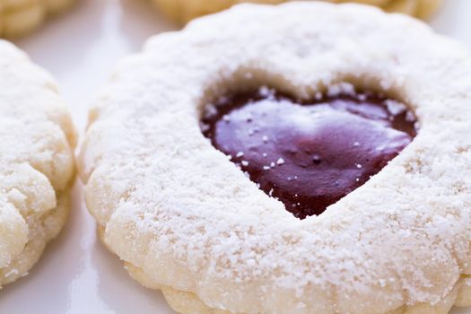 Linzer Torte cookies on white background with powdered sugar sprinkled on top.