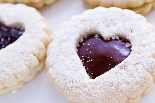 Linzer Torte cookies on white background with powdered sugar sprinkled on top.