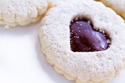 Linzer Torte cookies on white background with powdered sugar sprinkled on top.