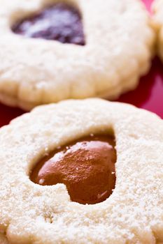 Linzer Torte cookies on red plate with powdered sugar sprinkled on top.