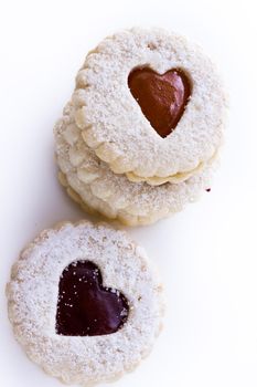 Linzer Torte cookies on white background with powdered sugar sprinkled on top.