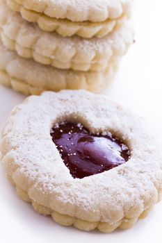 Linzer Torte cookies on white background with powdered sugar sprinkled on top.