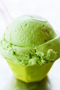 Green gelato in green plastic cup.