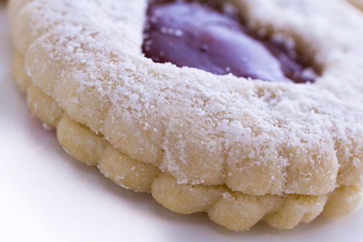 Linzer Torte cookies on white background with powdered sugar sprinkled on top.