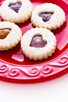 Linzer Torte cookies on red plate with powdered sugar sprinkled on top.