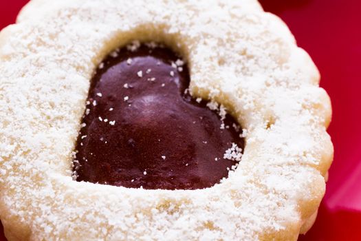 Linzer Torte cookies on red plate with powdered sugar sprinkled on top.