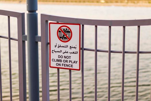 Warning signs in Arabic and English languages on the fence of the park.