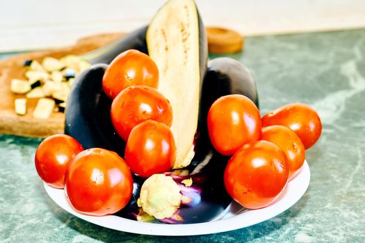 a plant or part of a plant used as food, typically as accompaniment to meat or fish, such as a cabbage, potato, carrot, or bean. Fresh tomatoes, eggplant for cooking on kitchen table