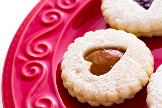 Linzer Torte cookies on red plate with powdered sugar sprinkled on top.