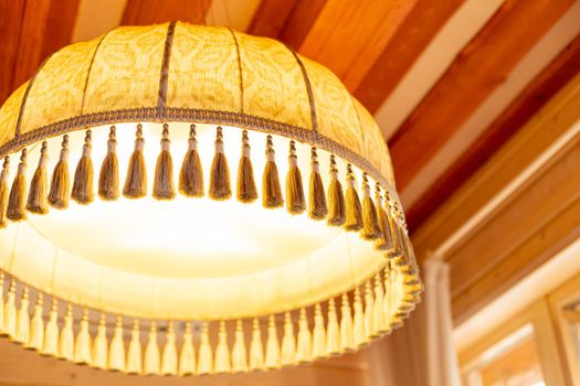 Large white fabric lampshade with fringe as an element of vintage decor. Old style retro lampshades