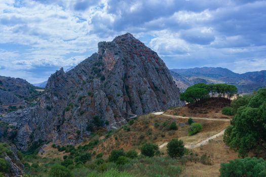 mountain landscape with a road leading to the dam of los caballeros in montejaque , malaga, spain with dramatic cloudy sky