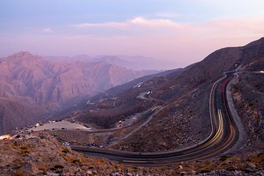 View from Jebael Jais mountain of Ras Al Khaimah emirate in the evening. United Arab Emirates, Outdoors. Light trails from the car