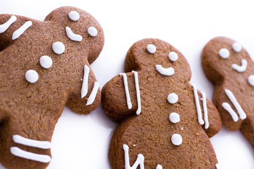 Homemade gingerbread cookies decorated with white icing on white background.