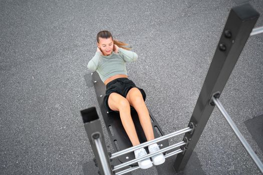 Sit-ups exercises. Active, fit sporty woman doing situps, exercising and training on fitness outdoor gym. One young, serious and athletic female exercising, working out and doing physical activity