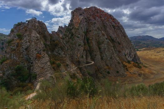 mountain landscape with a road leading to the dam of los caballeros in montejaque , malaga, spain with dramatic cloudy sky