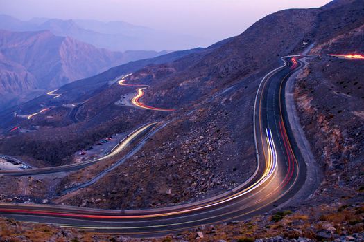 View from Jebael Jais mountain of Ras Al Khaimah emirate in the evening. United Arab Emirates, Outdoors. Light trails from the car