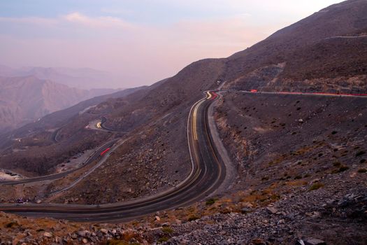 View from Jebael Jais mountain of Ras Al Khaimah emirate in the evening. United Arab Emirates, Outdoors. Light trails from the car